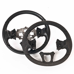 Two steering wheel shapes slightly overlapping. The background one is made from moulded ARPRO (expanded polypropylene) and has a metal insert. The foreground one is an ARPRO prototype so made from cut ARPRO