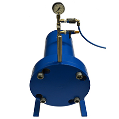 A blue pressure tank with a pressure gauge on the top with pipes coming out