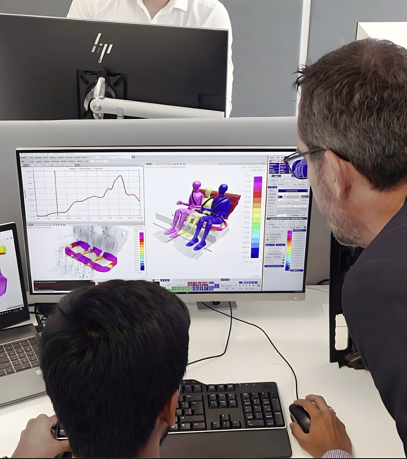Two gentleman looking at CAD and FEA simluation on computer screens
