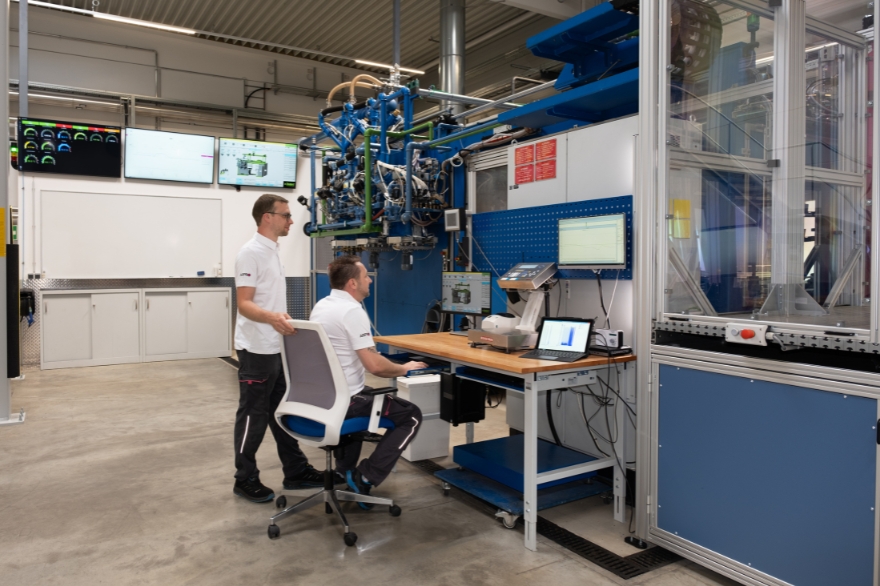 Two men at a desk in the lab, one sitting and one standing looking at a computer screen.